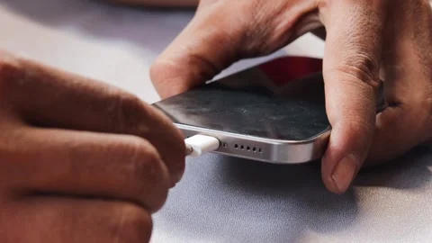 Asian man inserting a USB-C connector into a modern smartphone 스톡 동영상 347114464