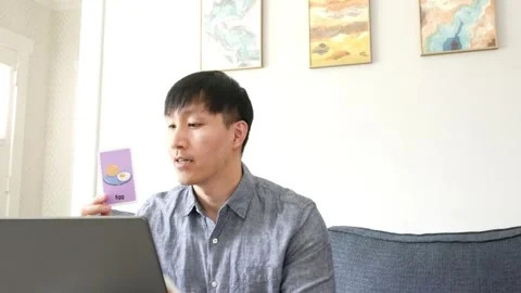 Asian man instructing an online class using flash cards Видео 247480069