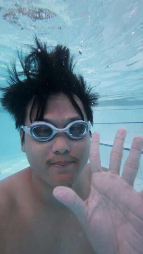 An Asian man jumping to a pool and weaving to camera. Underwater shot Stock Footage 339067007