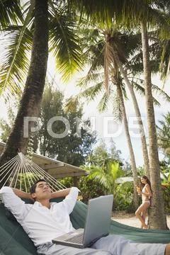 Asian man with laptop in hammock Stock Photos