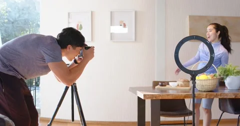 Asian man leaning into camera shooting woman posing by dining table with ring 스톡 동영상 335906979