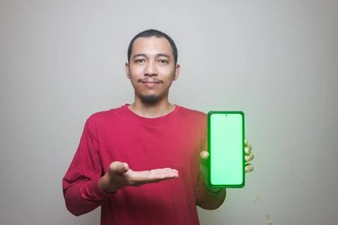 Asian man looking to camera, smiling and showing empty blank white copy spa.. Stock Photos