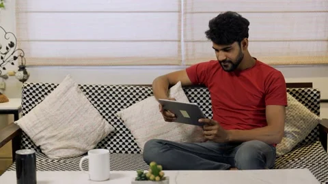 Asian man looking at tablet screen watching online lesson and movie while sit Stock-Footage 155577409