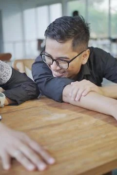 Asian man lying on the table while talk happy with woman Stock Photos