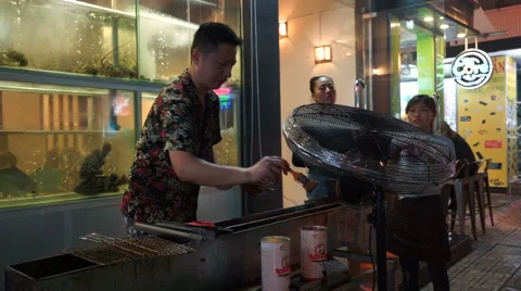 Asian man is making a barbeque on the street's restaurnt at night time Stock Footage 67420818