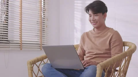 Asian man making facetime video calling with smartphone at home. He's waving  Stock Footage 167724040