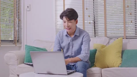 Asian man making facetime video calling with smartphone at home. He's waving  Stock Footage 167724451