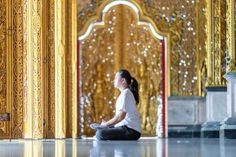Asian Man meditates on the ground with reflection in the sunlight pouring i.. Stock Photos