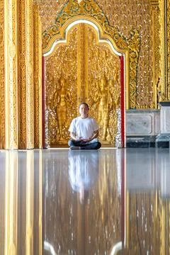 Asian Man meditates on the ground with reflection in the sunlight pouring i.. Stock Photos