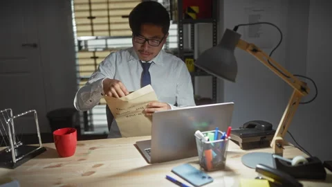 Asian man in office examining documents labelled 'fraud case' at night indi.. Stock Footage 276953933
