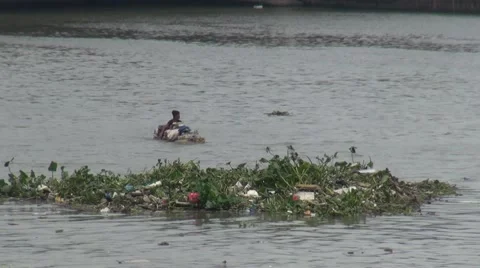 Asian man paddles using  his hands up a polluted river in Manila Stock Footage 51453568