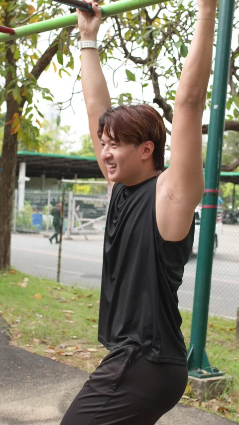 Asian Man Performing Hanging Leg Raises at Outdoor Park Gym Stock Footage 335734234