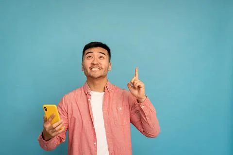 Asian man pointing upward while holding phone. Foto stock