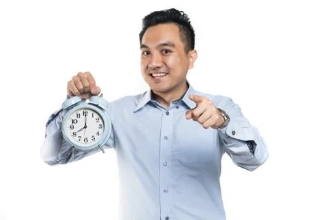 Asian man pointing while holding alarm clock Stock Photos