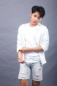 Asian man posing standing head straightwhile hands buttoning shirt sleeves Stock Photos