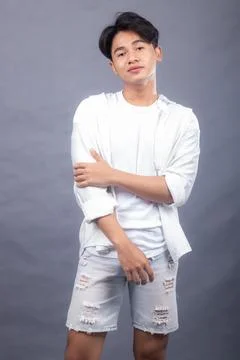 Asian man posing standing head straight while his hands hold his shirt sleeves Stock Photos