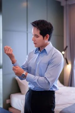 Asian Man Preparing For Work Rolling Up His Light Blue Shirt Sleeves Gettin.. Stock Photos