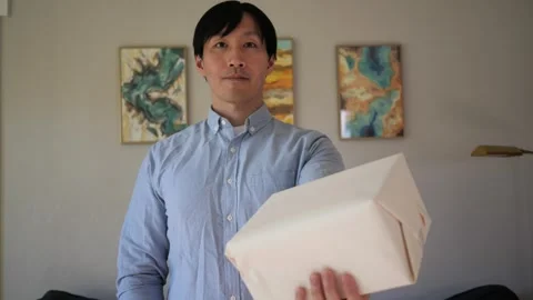 Asian man presenting a box wrapped gift Vidéo 295315508