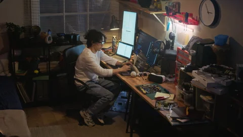 Asian Man Programming on Laptop with Multiple Monitors at Night Stock Footage 338422928