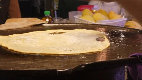 Asian man puts thin dough sheet onto hot pan and adds butter Stock Footage 285390281