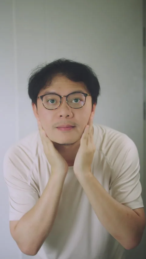 Asian Man Putting on Glasses After Waking Up, Checking Face in Bathroom Mirror Stock Footage 337769657