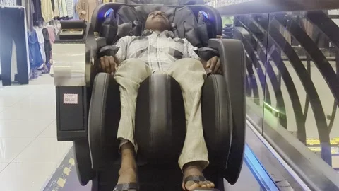 Asian Man Relaxing in Electric Massage Chair at Shopping Mall Stock Footage 327770657