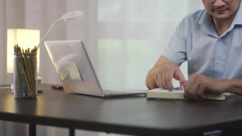 Asian man, remote work and writing notes at laptop in home office for plannin Stock Footage 244799218