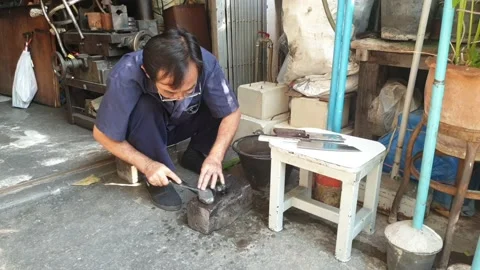 Asian man is sharpening knives using knife sharpening stone in workshop Stock Footage 144519698