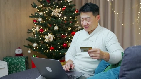 Asian man shopping online using laptop and credit bank card sitting at home on  Stock Footage 219913102