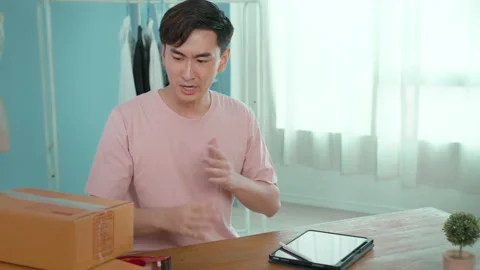 An Asian man is showing clothes in front of smartphone  live streaming at his Stock-Footage 172008153