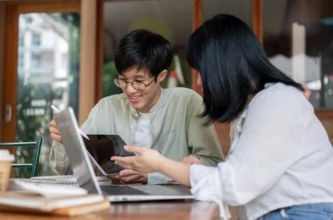 An Asian man is showing something on his digital tablet to his female colle.. Stock Photos