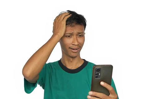 An Asian man shows a sad expression while looking at a smartphone screen. Stock Photos