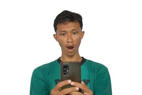 An Asian man shows a surprised expression while looking at the smartphone s.. Stock Photos