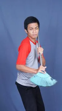 Asian man  sing with a broom isolated blue background Stock Photos