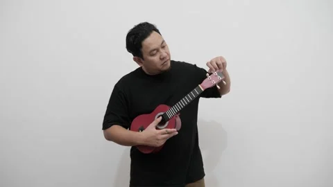 Asian man singing while playing ukulele Stock Footage 293532213