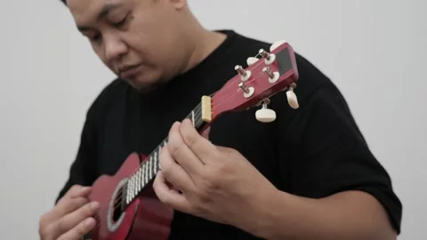 Asian man singing while playing ukulele Stock Footage 293533014