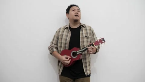 Asian man singing while playing ukulele Stock Footage 293533300