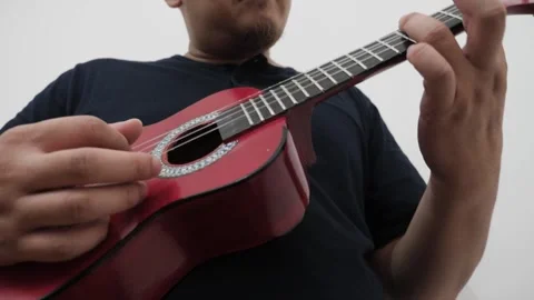 Asian man singing while playing ukulele Stock Footage 293533639