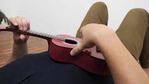 Asian man singing while playing ukulele Stock Footage 293533934