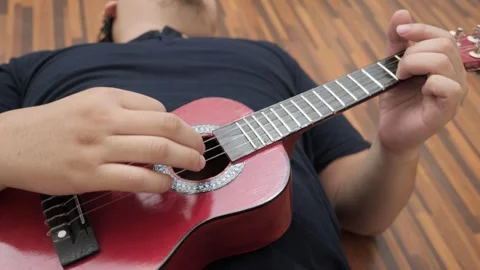 Asian man singing while playing ukulele Stock Footage 293533939