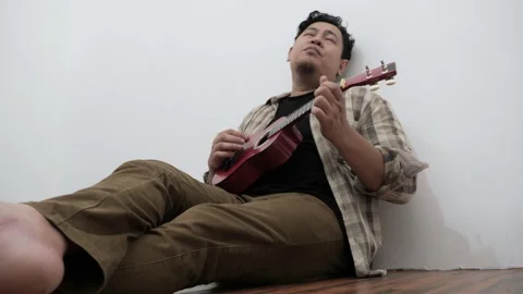 Asian man singing while playing ukulele Stock-Footage 293534098