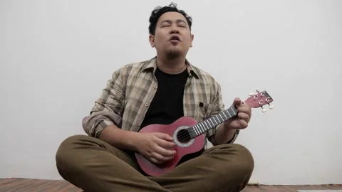 Asian man singing while playing ukulele Video stock 293534141