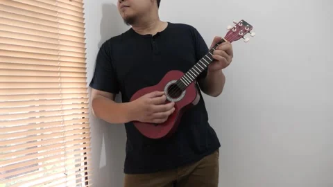 Asian man singing while playing ukulele Stock Footage 293534373