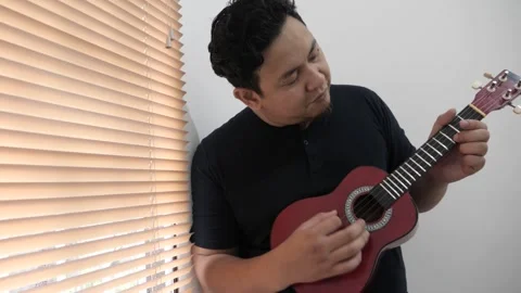 Asian man singing while playing ukulele Video stock 293534524