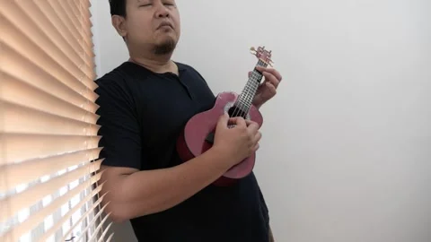 Asian man singing while playing ukulele Video stock 293534577