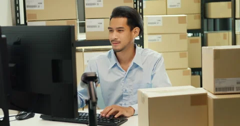 Asian man sit front desk computer use barcode machine scan record online data. Stock Footage 229645937