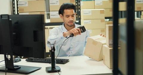 Asian man sit front desk computer use barcode machine scan record online data. Stock Footage 229646653