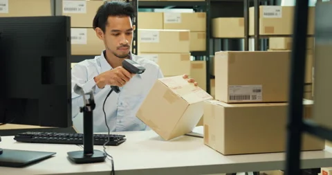 Asian man sit front desk computer use barcode machine scan record online data. Stock Footage 229647083