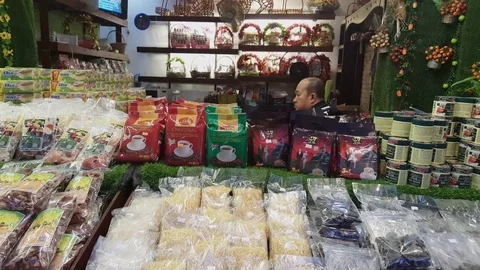 Asian man sits inside coffee, nuts and gift baskets shop, Vientiane, Laos Vídeos de archivo 75560089