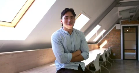 Asian man sitting on bench under skylights in loft office, reacting to Stock Footage 342030921